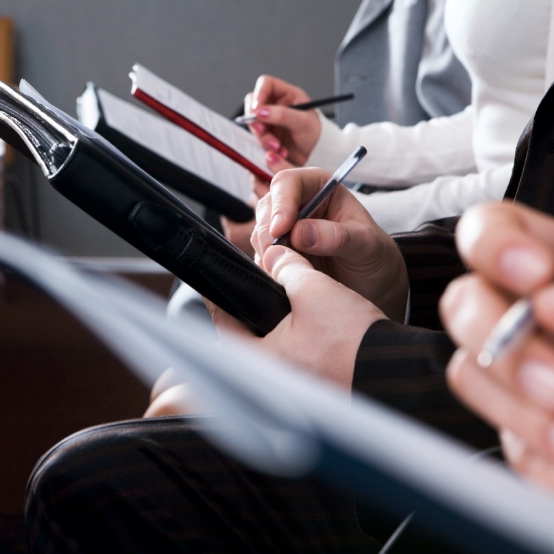 Attendees take notes during a business seminar.