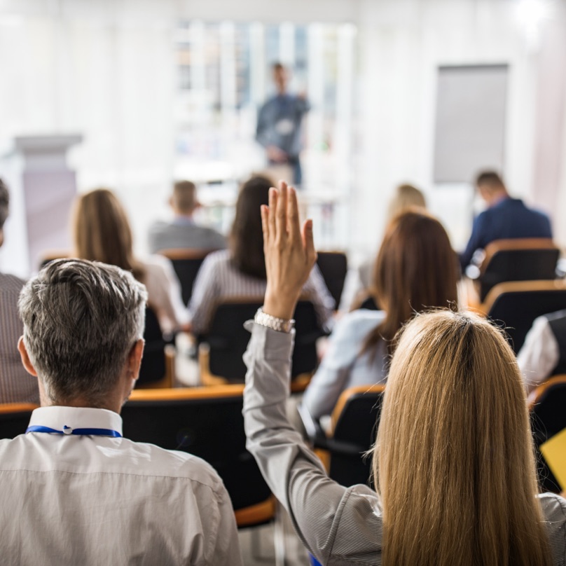 Attendee raises a hand during a conference presentation.