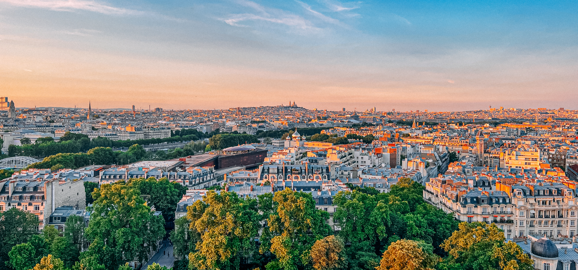 Aerial view of Paris, France with lush green trees at sunset.