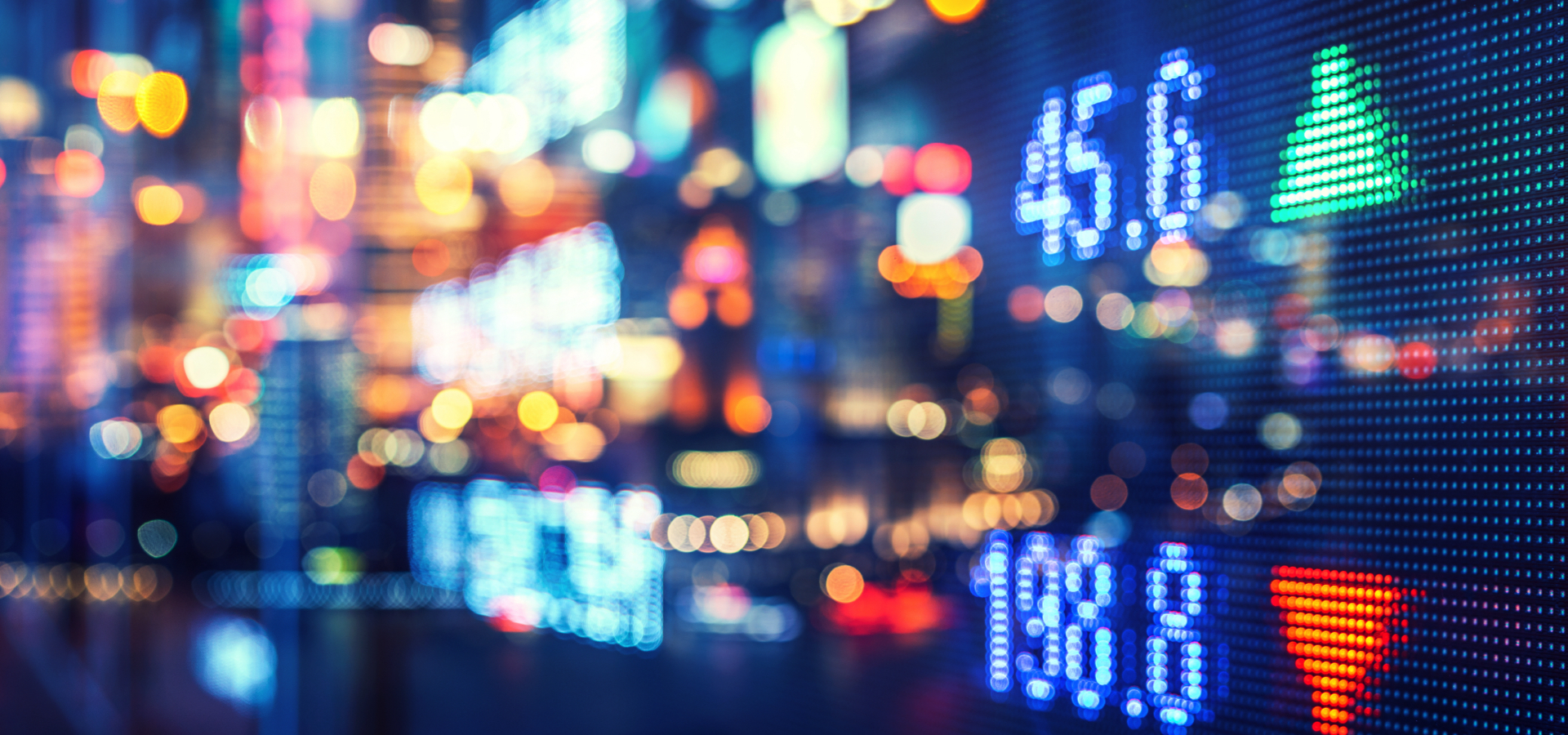 Abstract financial markets numbers overlaying cityscape with multicolor lights.