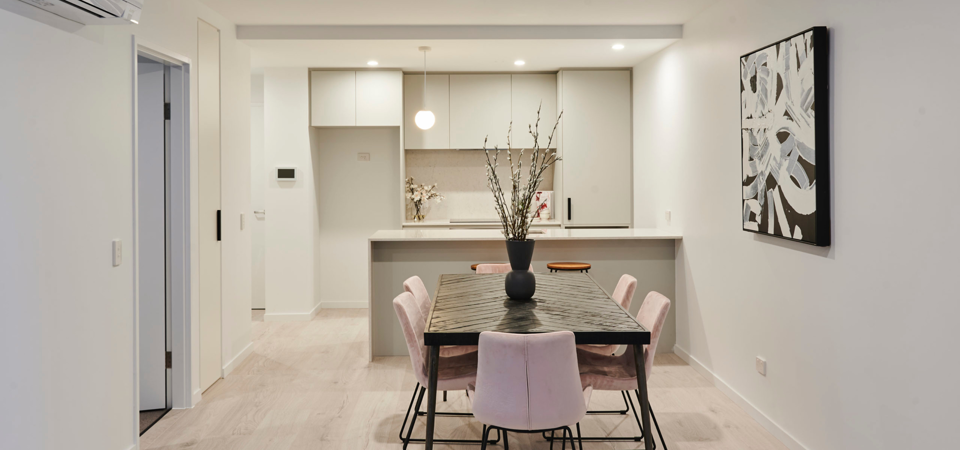 A dining table with chairs in front of a kitchen.